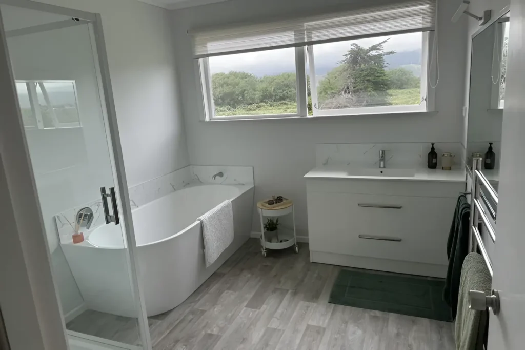 Modern bathroom renovations Wellington in New Zealand featuring a freestanding bathtub, glass shower, and sleek vanity.