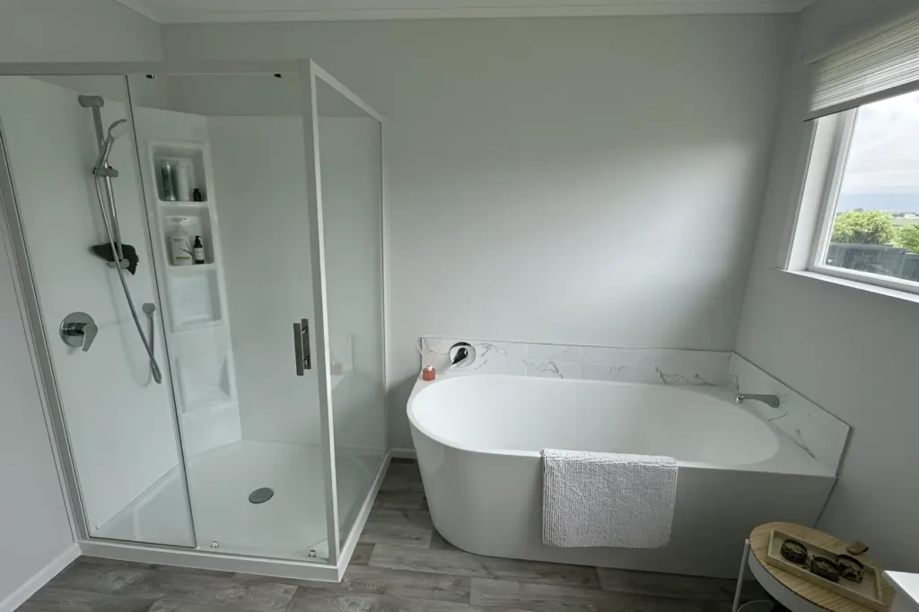 Stylish bathroom renovations Wellington in New Zealand with a glass shower, sleek bathtub, and bright natural light.